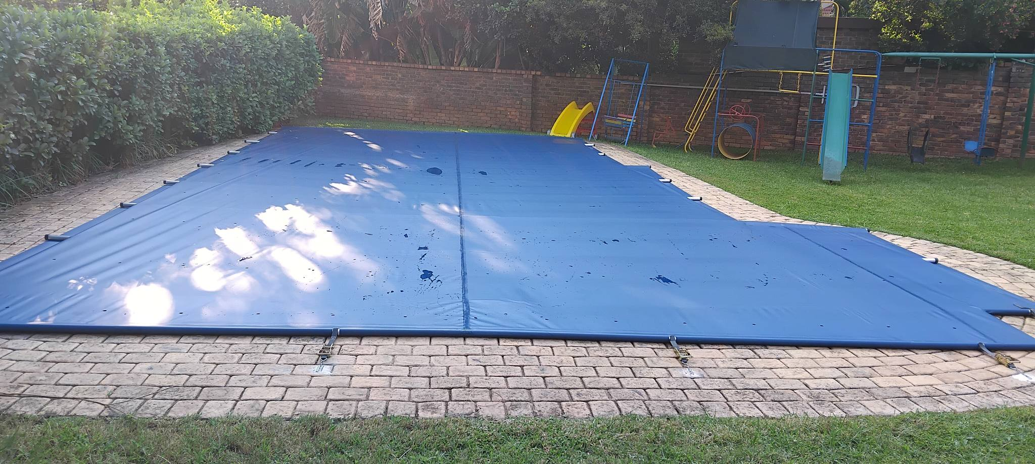 Dark charcoal pool cover with aluminium roller system at modern home