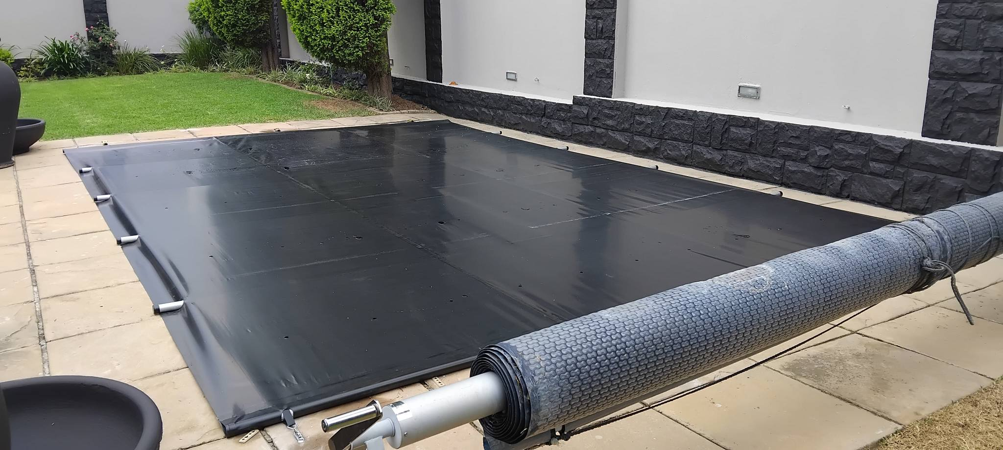 Large blue pool cover installation with play equipment in background